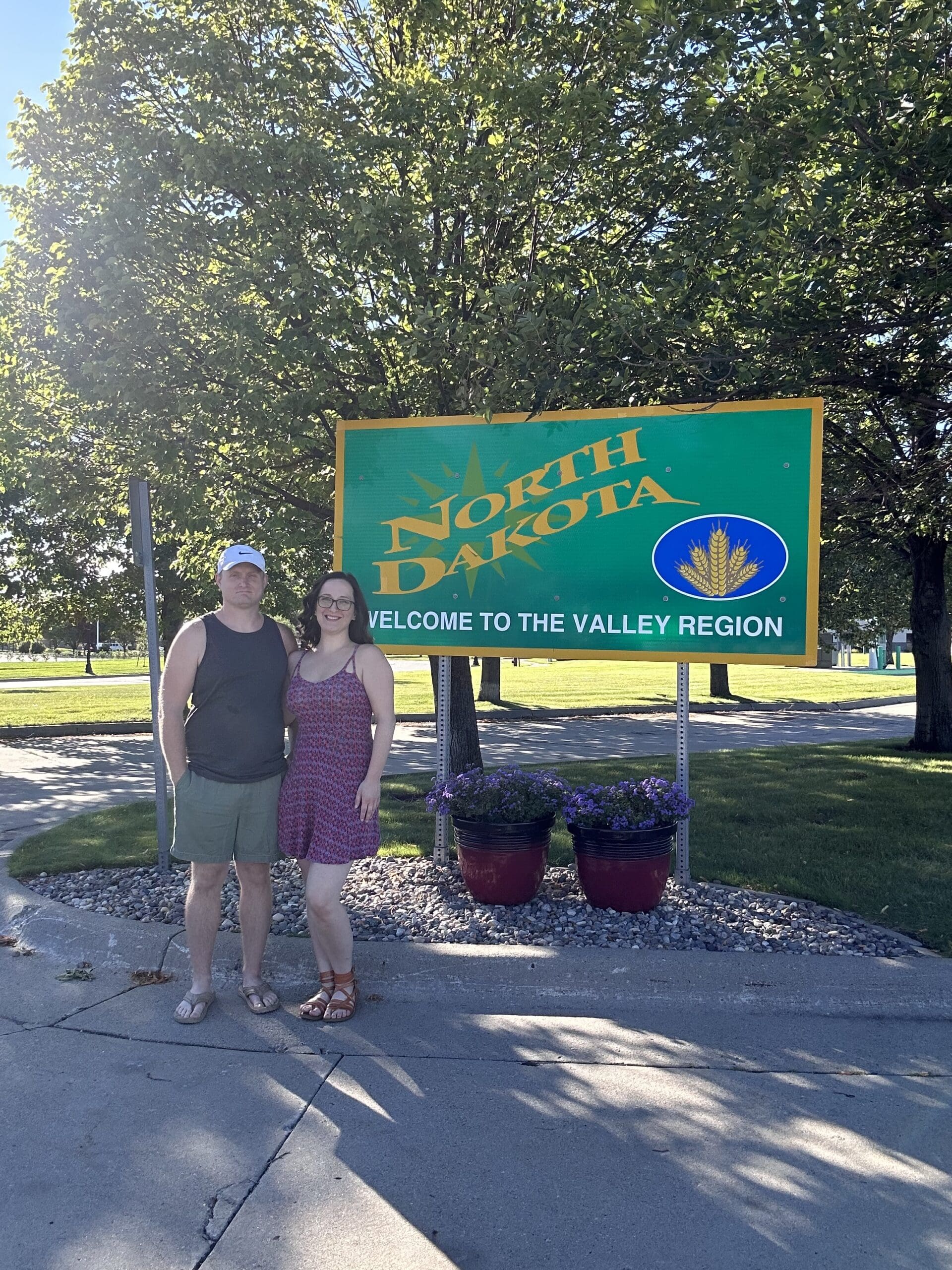 Payton Bendure, owner of Payton B Virtual Solutions, taking a photo in front of a north dakota state sign, sharing the lessons she's learned in two months of full time travel, and how it relates to her business.